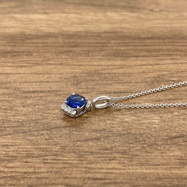 A blue sapphire and diamond pendant on a wooden table.