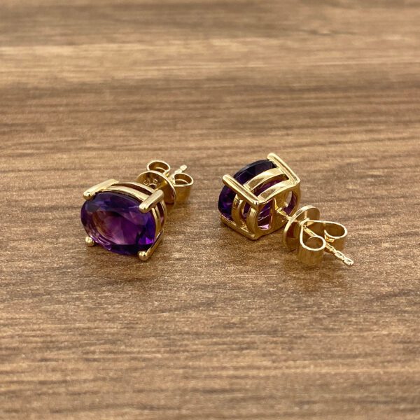 Gold earrings with purple amethyst stones.