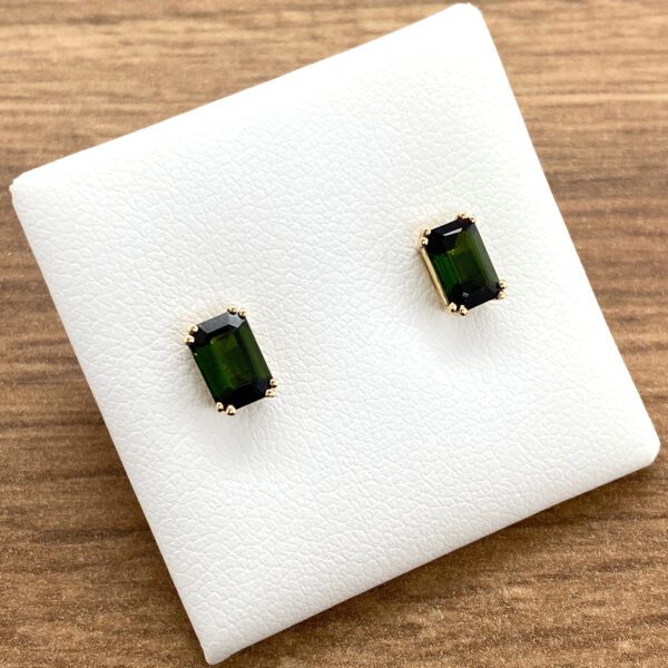 Gold earrings with green gemstones.