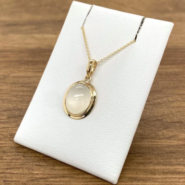 Gold chain with oval moonstone pendant.