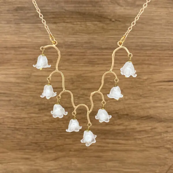 Gold chain necklace with lily of the valley pendants.