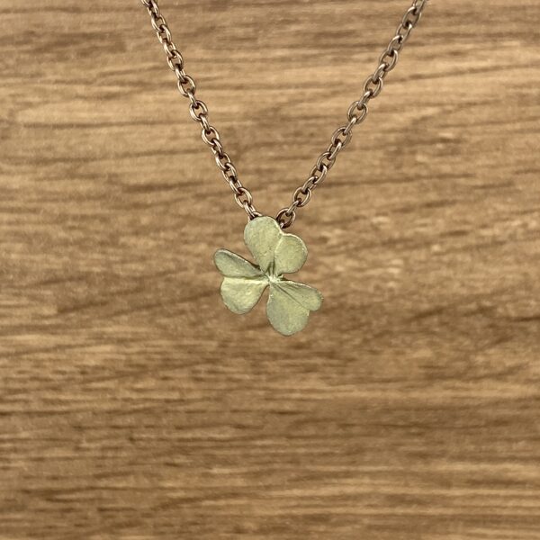 Gold chain necklace with clover pendant.