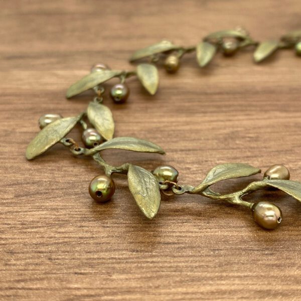 Bronze leaf and pearl necklace on wood.