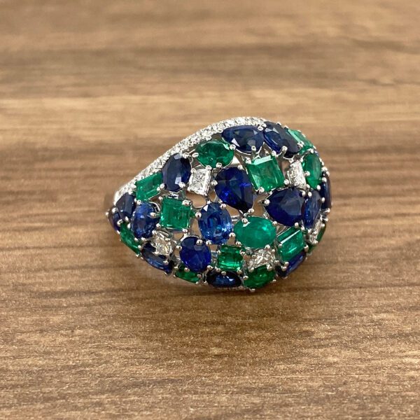 Emerald and sapphire ring on wood.