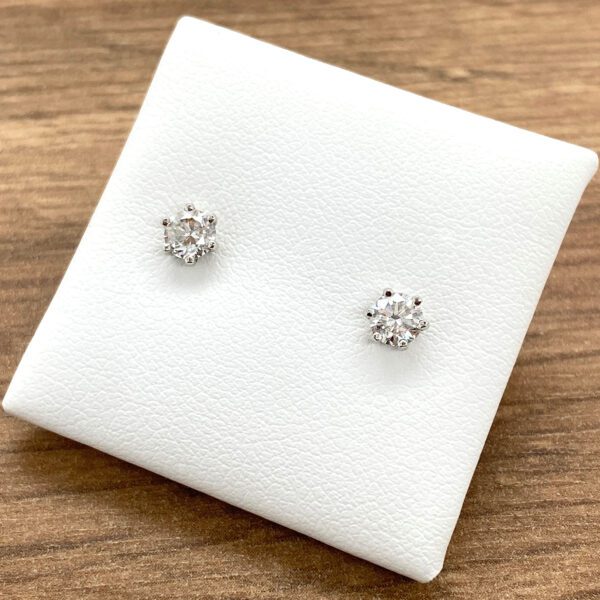 Diamond stud earrings on white display.