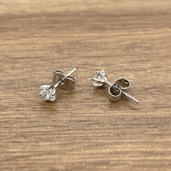 Two silver diamond stud earrings.