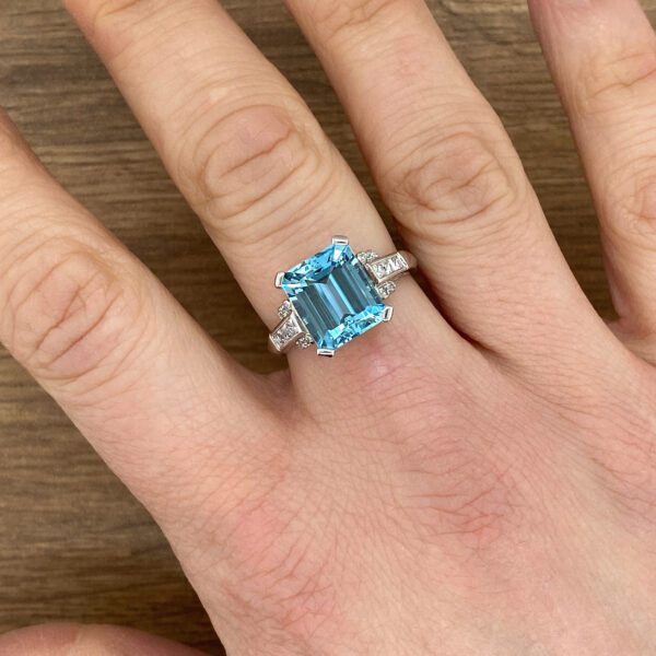 Hand wearing an aquamarine ring with diamonds.