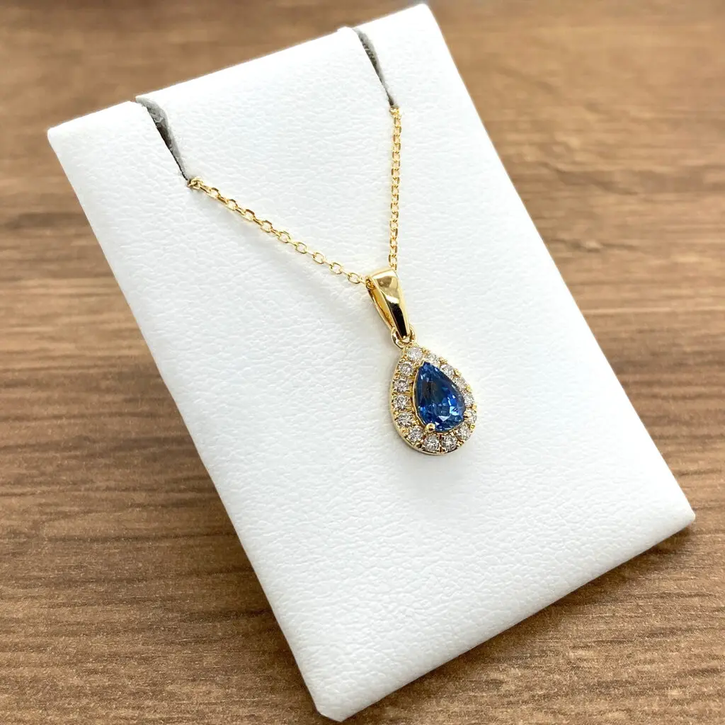 Gold necklace with pear-shaped blue sapphire pendant.