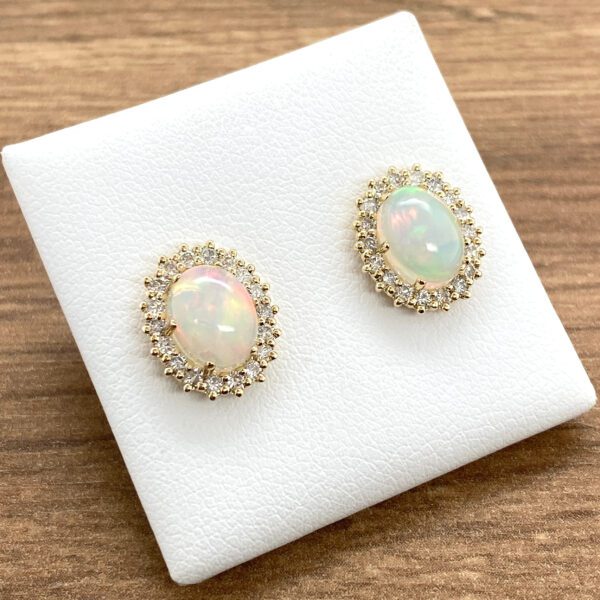 Opal and diamond earrings on white display.