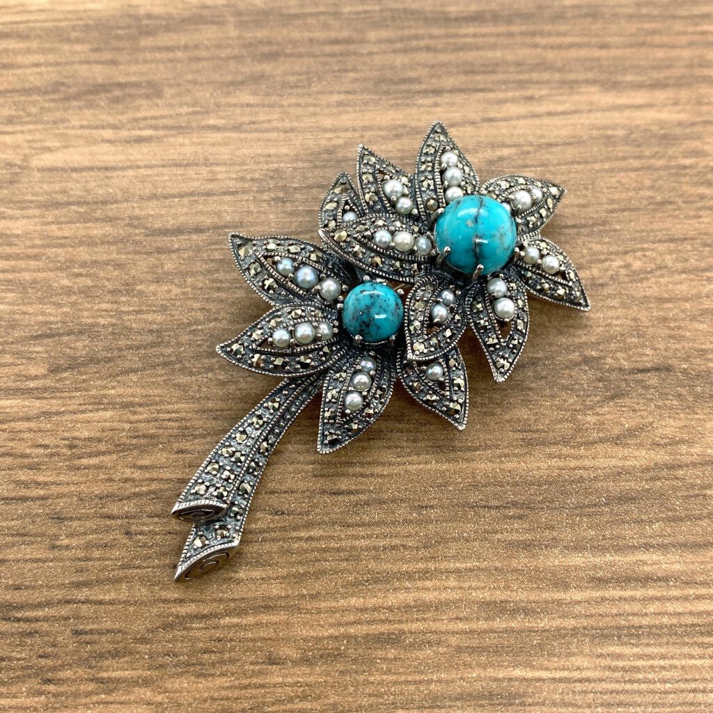 Silver floral brooch with turquoise stones.