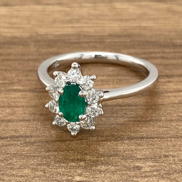 Emerald and diamond ring on wooden surface.