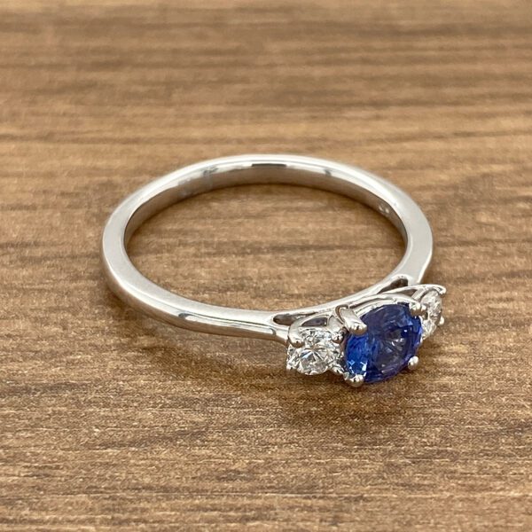 Blue sapphire and diamond ring on wood.