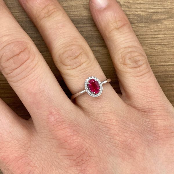 Ruby and diamond engagement ring on finger.