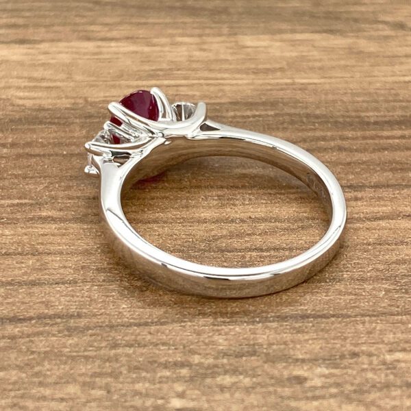 Silver ring with red gem and diamonds.