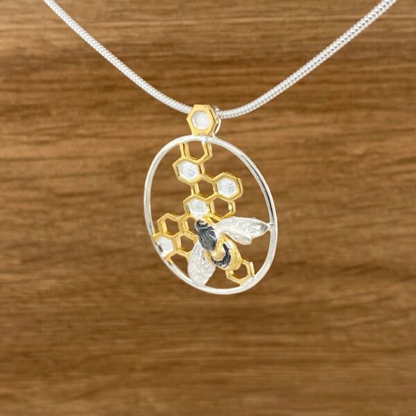 Silver necklace with bee and honeycomb pendant.