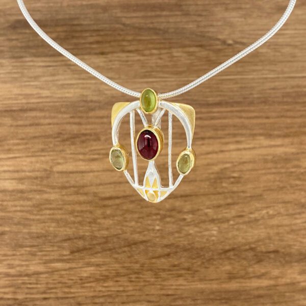 Silver and gold pendant with red and green stones.