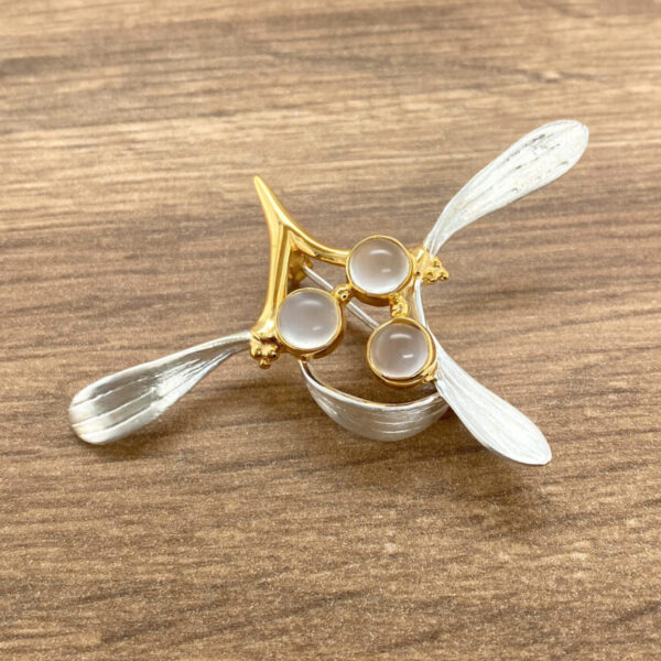 Gold and silver brooch with three white stones.