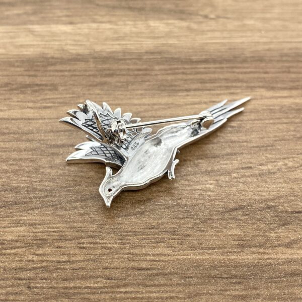 Silver pheasant brooch with detailed design.