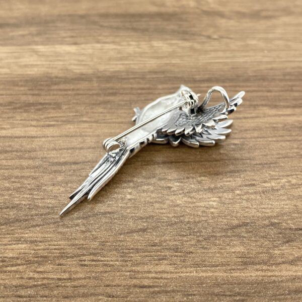 Silver bird brooch with wings spread.