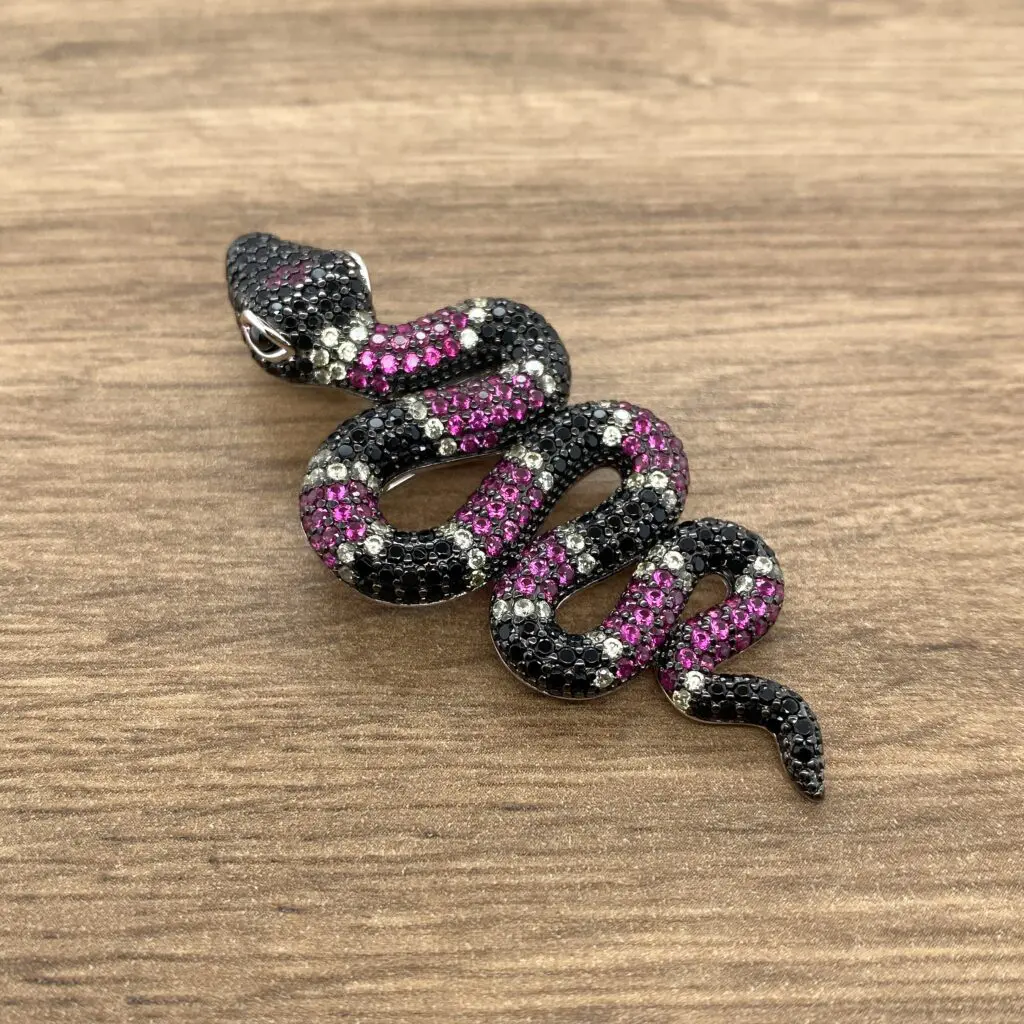 Black and pink jeweled snake pendant.