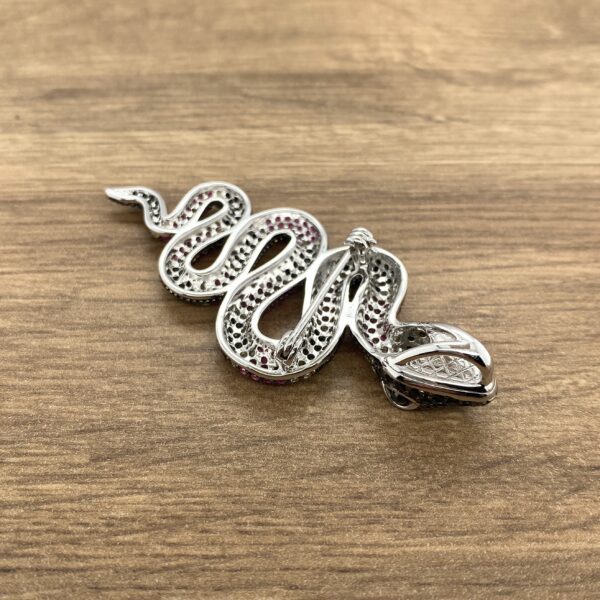 Silver snake brooch with pink stones.