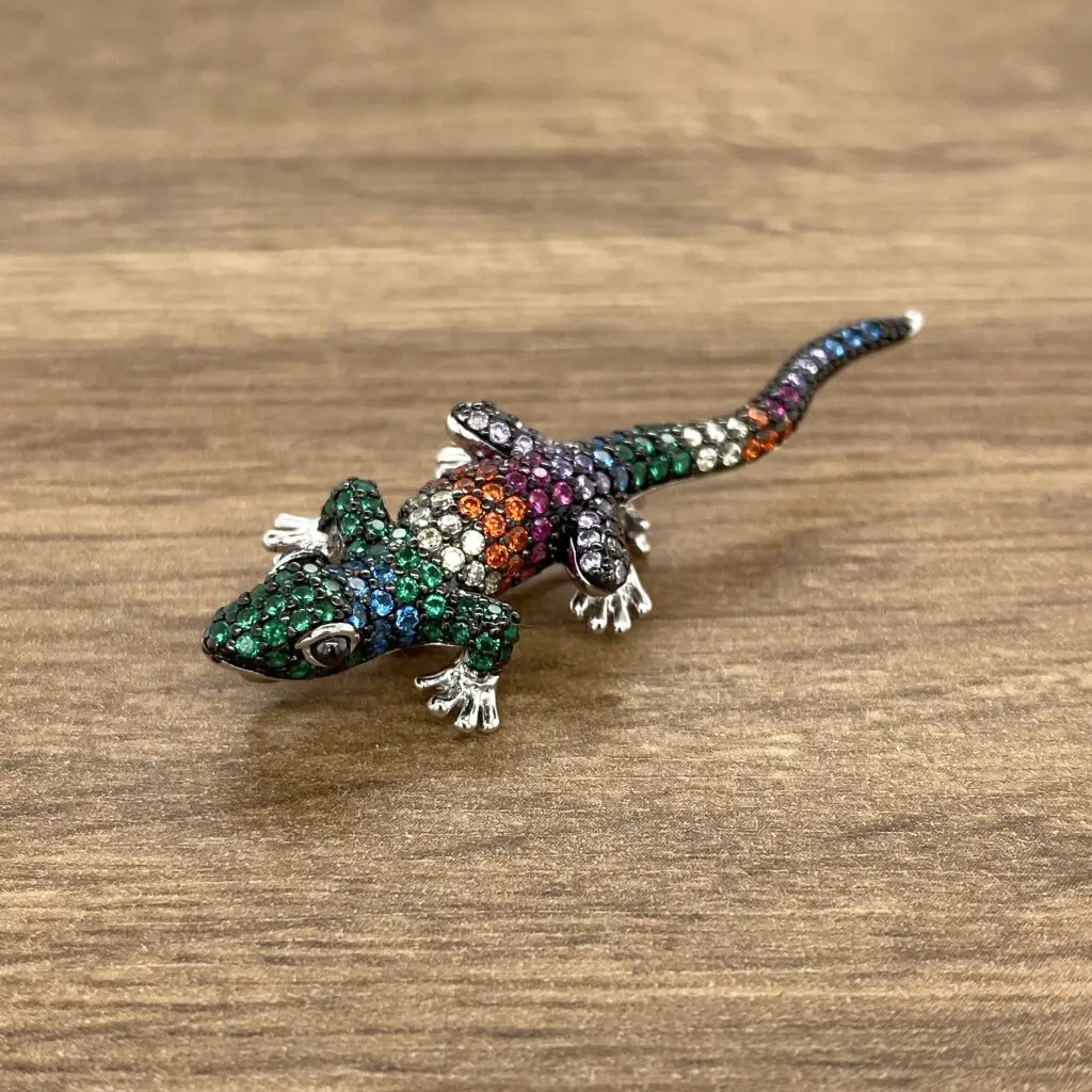 Gemstone lizard brooch on wood background.