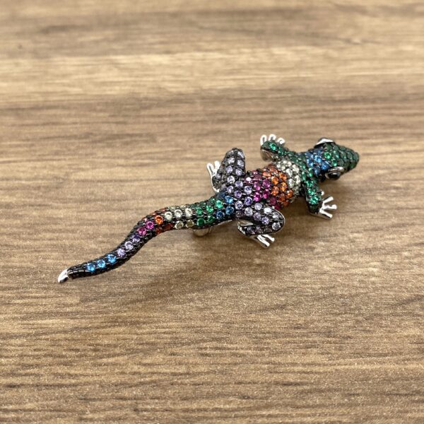 Gemstone lizard brooch on wood grain.