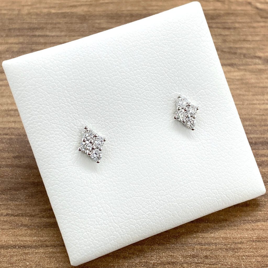 Diamond stud earrings on white display.