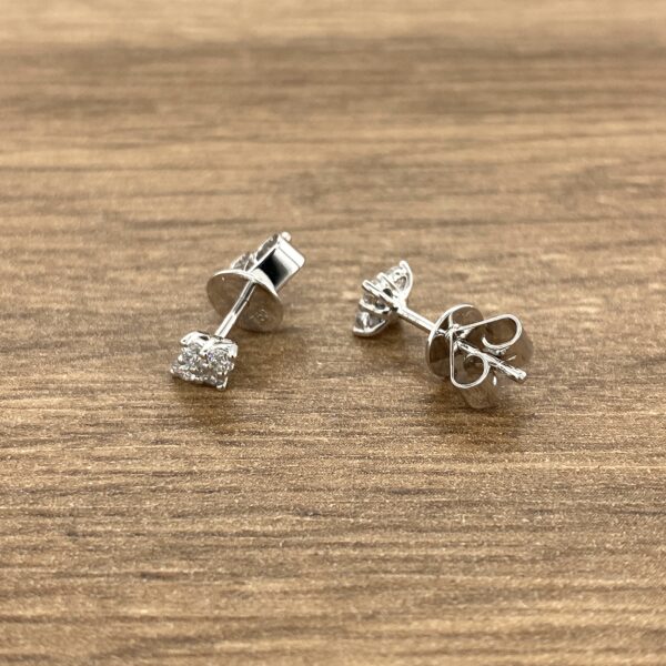 Pair of diamond stud earrings on wood.