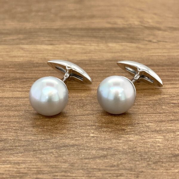 Silver cufflinks with gray pearls.
