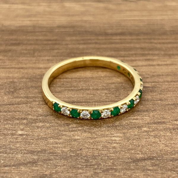 Gold eternity band with emeralds and diamonds.