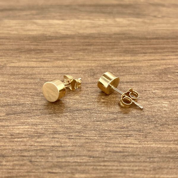 Gold cylindrical stud earrings.