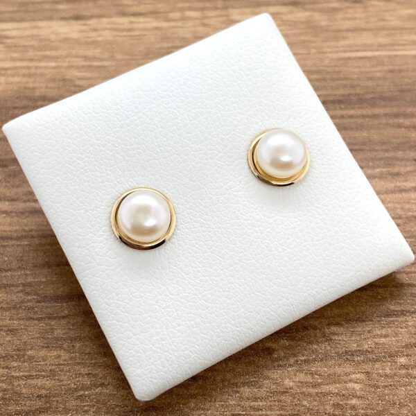 Gold pearl stud earrings on display.