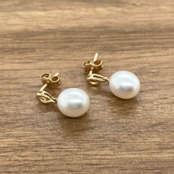 Gold pearl dangle earrings.