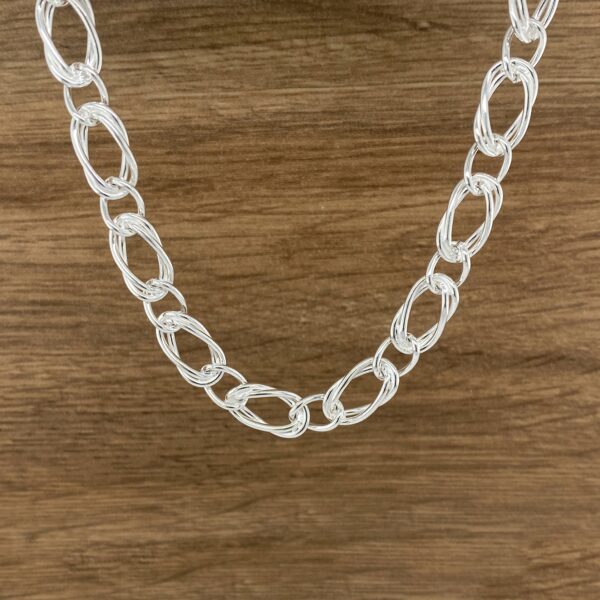 Silver chain necklace on wood background.