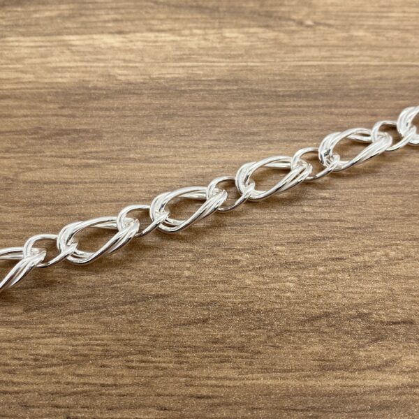 Silver chain link bracelet on wood.