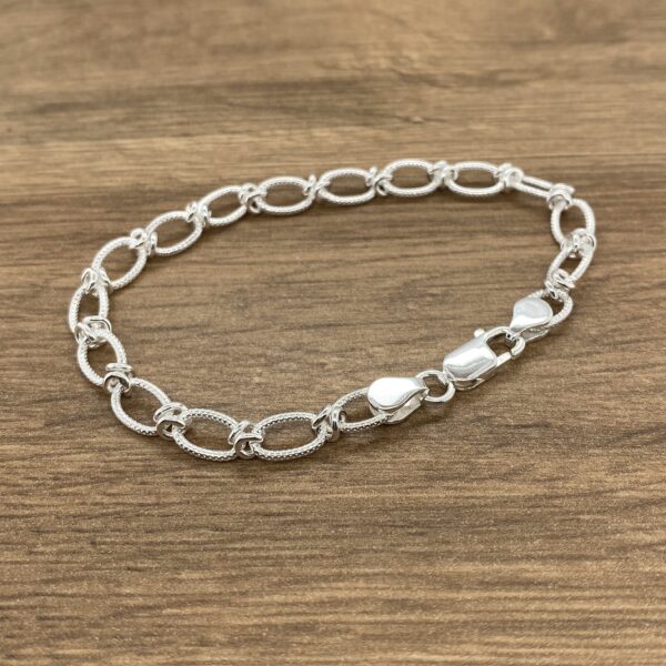 Silver oval link bracelet on wood.