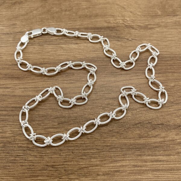 Silver chain necklace on wood.