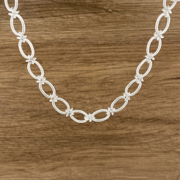 Silver barbed wire oval necklace.