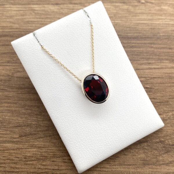 Oval garnet pendant necklace in gold.