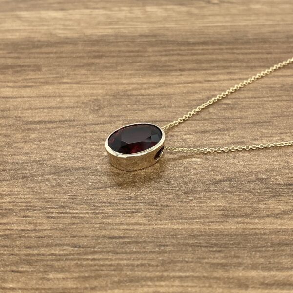 Oval garnet pendant on gold chain.