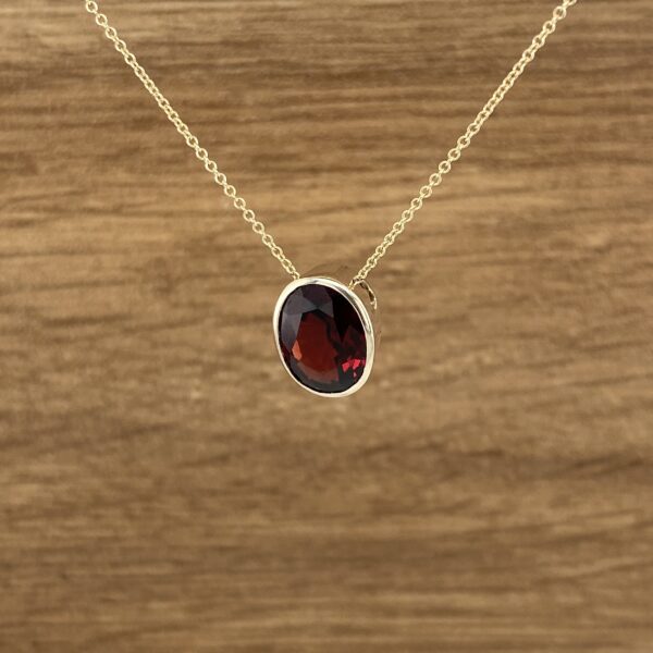 Oval garnet pendant on gold chain.