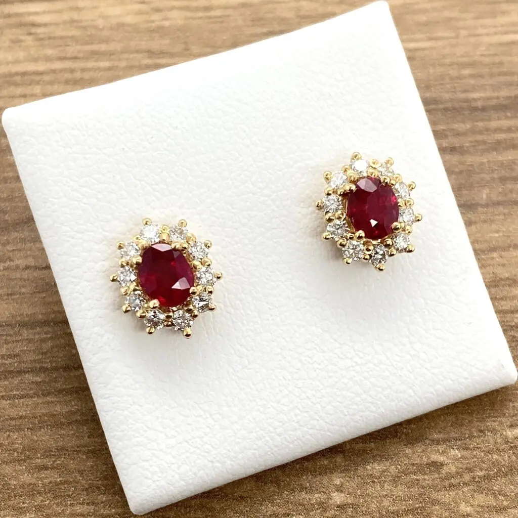 Gold earrings with red gemstones displayed.
