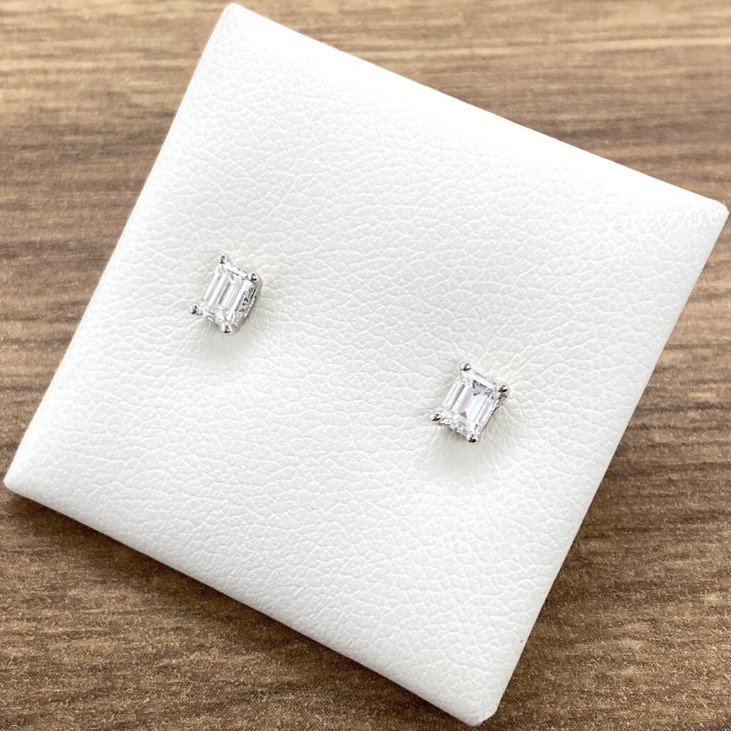 Diamond stud earrings on white display.