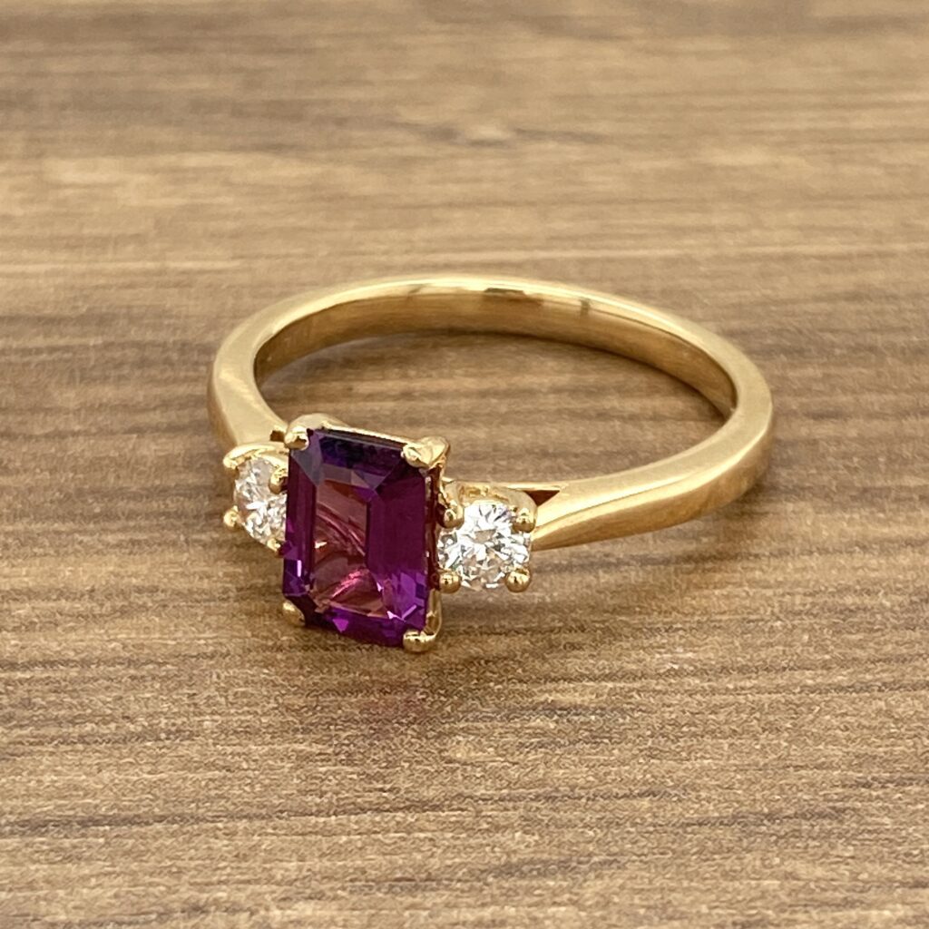Gold ring with purple and white stones.